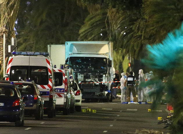 French police forces and forensic officers stand next to a truck that ran into a crowd celebrating the Bastille Day national holiday on the Promenade des Anglais killing at least 60 people in Nice